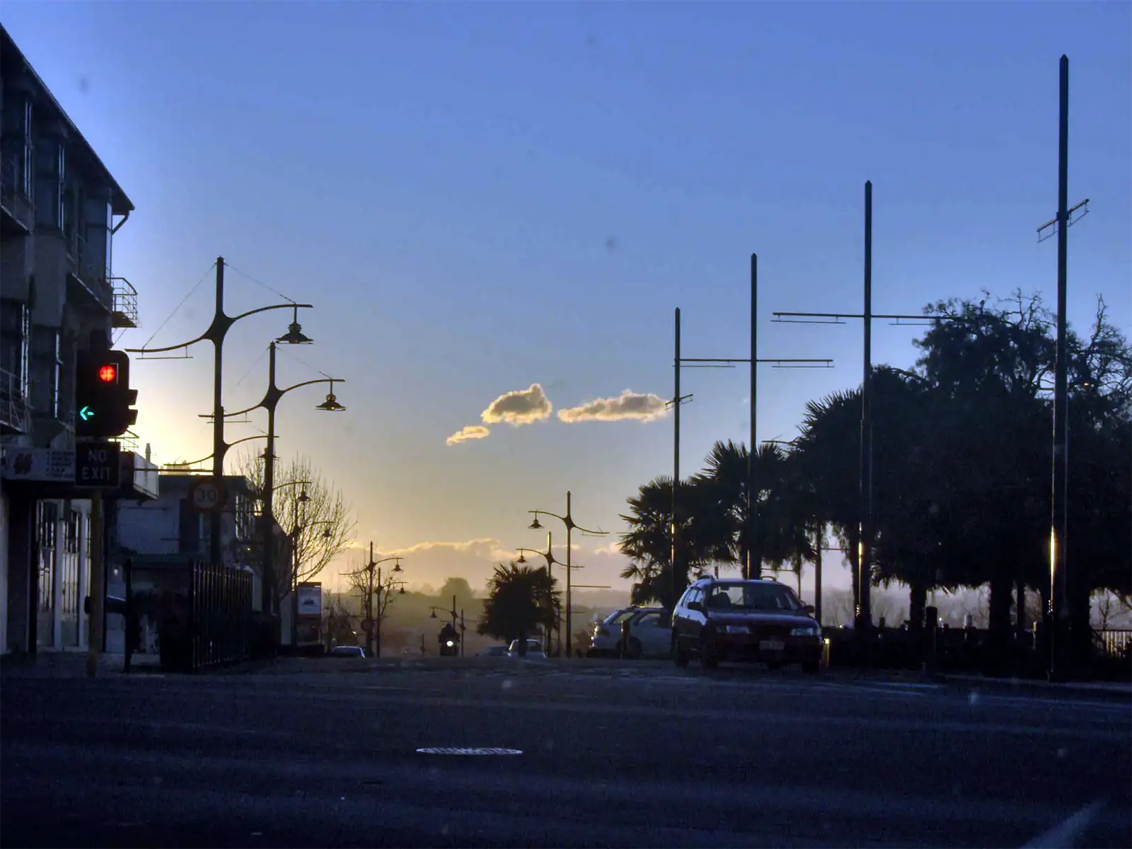 Palmiers et réverbères en ombre chinoise au coucher du soleil sur une avenue de Timaru, en Nouvelle-Zélande
