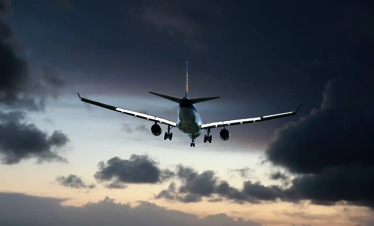 Avion de ligne en approche, train d’atterrissage sorti, sous un ciel d’orage au crépuscule