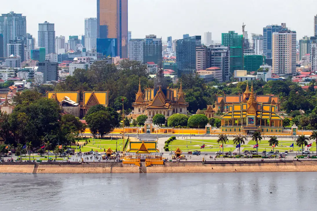 Le Palais royal de Phnom Penh et ses toits dorés au bord du fleuve, devant les tours du centre-ville