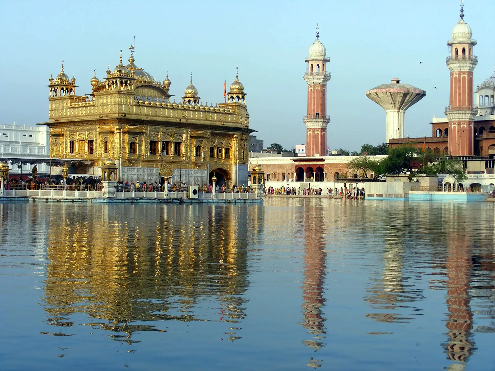 Le temple d’or d’Amritsar et les tours de son enceinte se reflétant dans les eaux calmes du bassin sacré