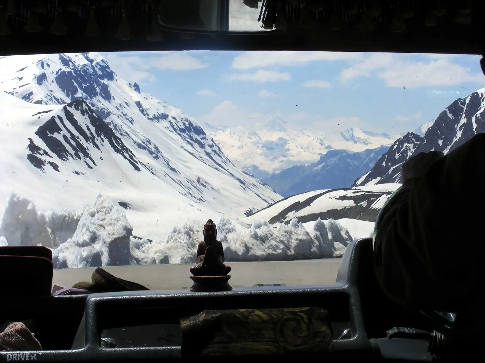 Sur la route Leh – Manali, murs de neige et sommets vus par le pare-brise, un petit Bouddha sur le tableau de bord