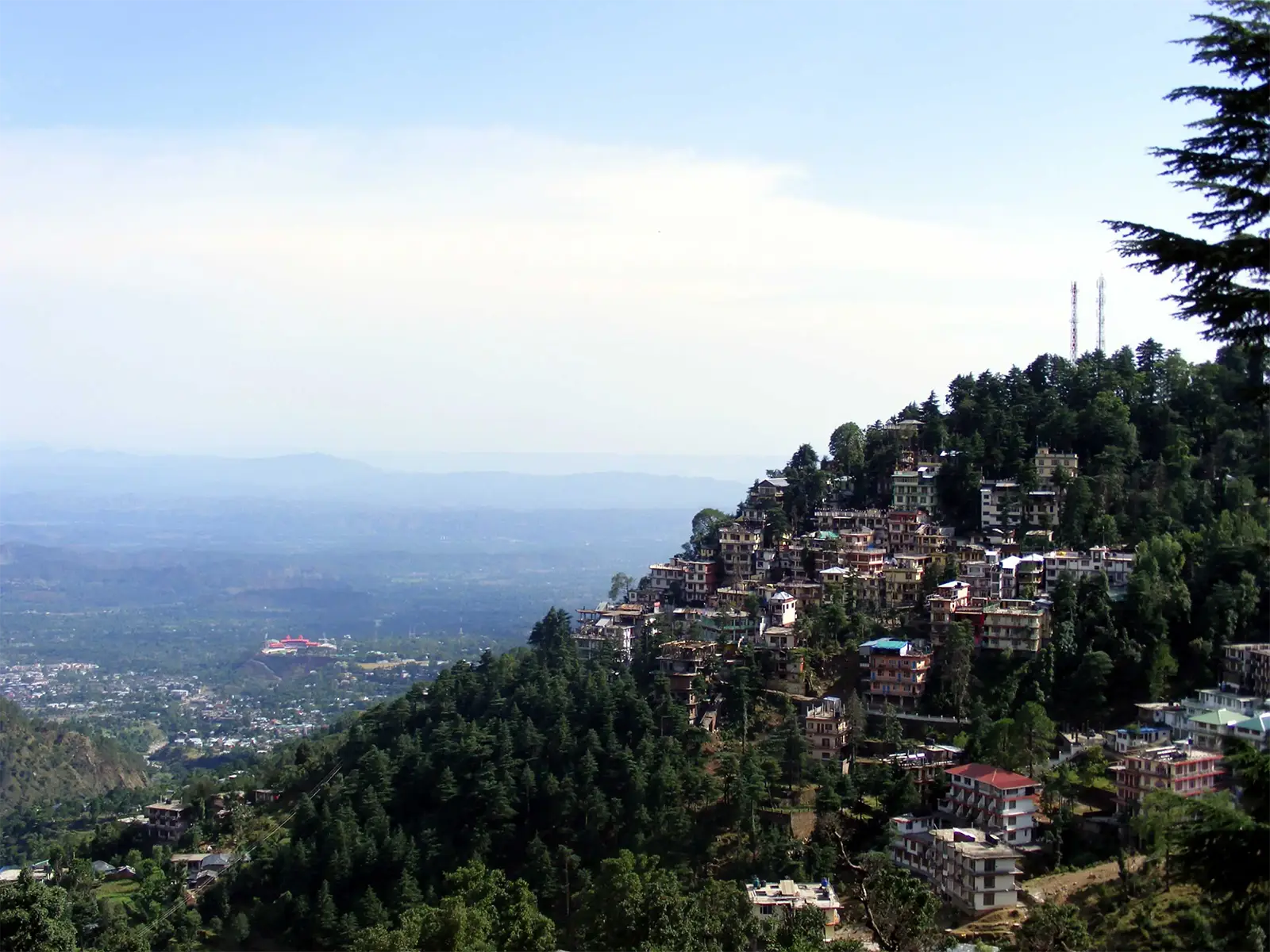 McLeod Ganj étagée sur sa crête boisée, au-dessus de la plaine brumeuse de Dharamsala